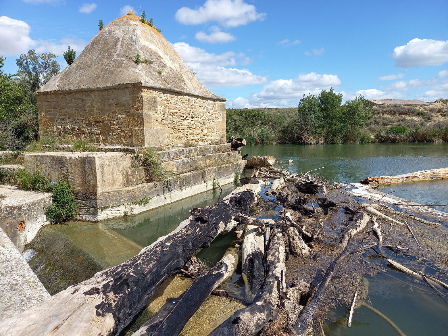 troncos en el río Aragón y una construcción de piedra